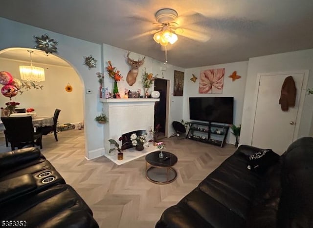 living room with arched walkways and ceiling fan with notable chandelier