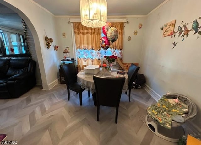 dining area featuring an inviting chandelier, arched walkways, crown molding, and baseboards