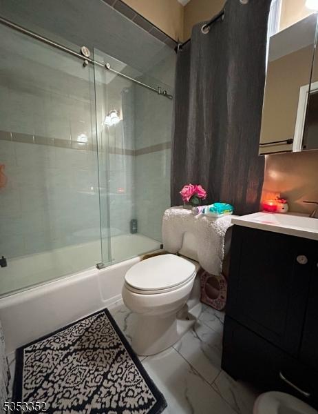 bathroom featuring vanity, marble finish floor, combined bath / shower with glass door, and toilet