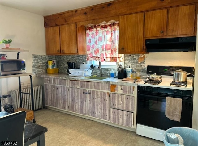 kitchen with a sink, stainless steel microwave, radiator heating unit, range with gas stovetop, and under cabinet range hood
