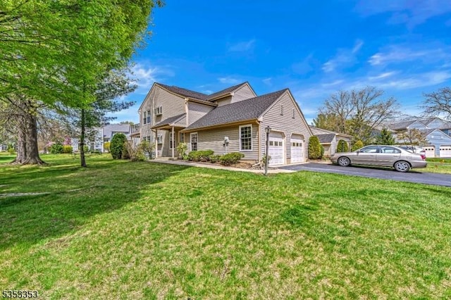 view of side of home with asphalt driveway, a yard, and an attached garage
