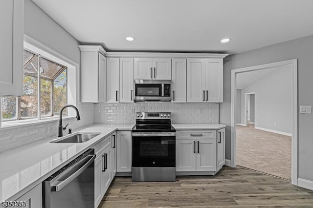 kitchen with stainless steel appliances, a sink, light countertops, tasteful backsplash, and recessed lighting