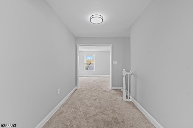 corridor featuring an upstairs landing, light colored carpet, and baseboards