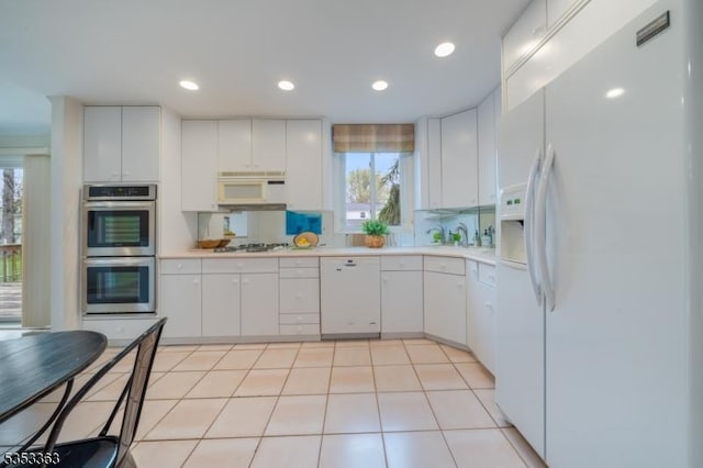 kitchen featuring white cabinets, white appliances, light countertops, a wealth of natural light, and backsplash