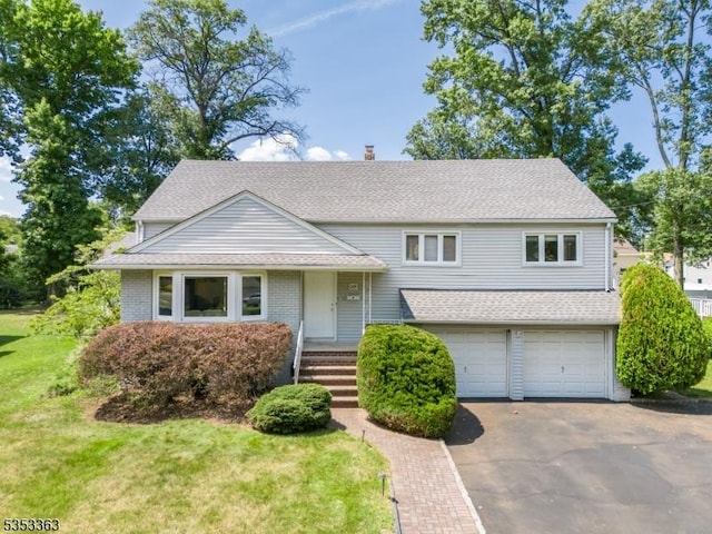 tri-level home featuring driveway, a chimney, roof with shingles, a front lawn, and an attached garage