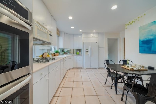 kitchen with light countertops, white cabinetry, light tile patterned flooring, and white appliances