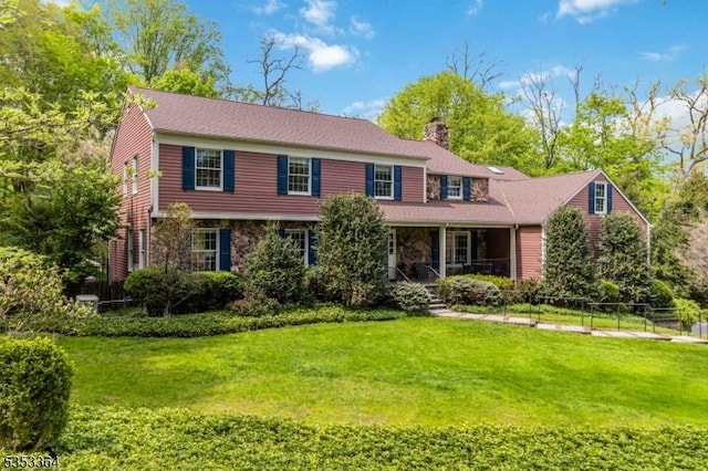 view of front of house featuring a porch, a chimney, fence, and a front yard