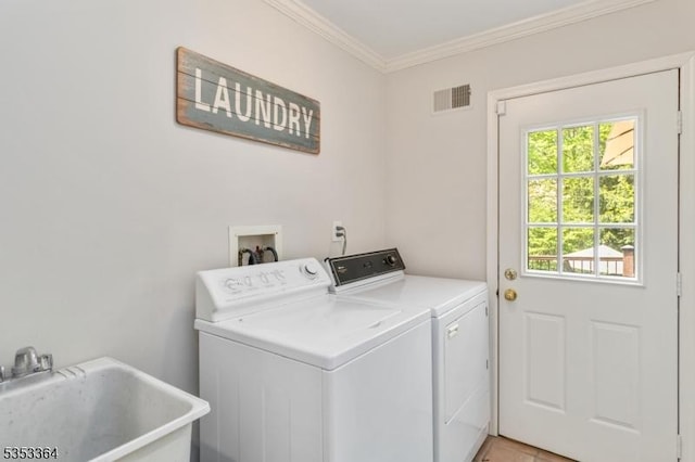 washroom featuring laundry area, visible vents, ornamental molding, washing machine and dryer, and a sink