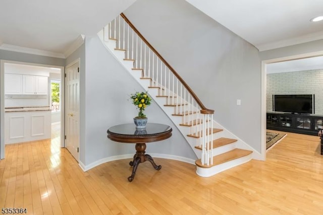 stairs with ornamental molding and hardwood / wood-style floors