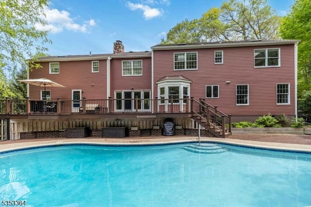 outdoor pool with stairway and a deck