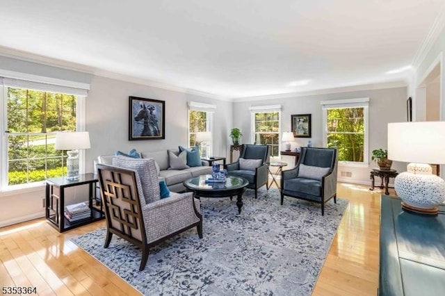 living area with crown molding, light wood-type flooring, and a healthy amount of sunlight