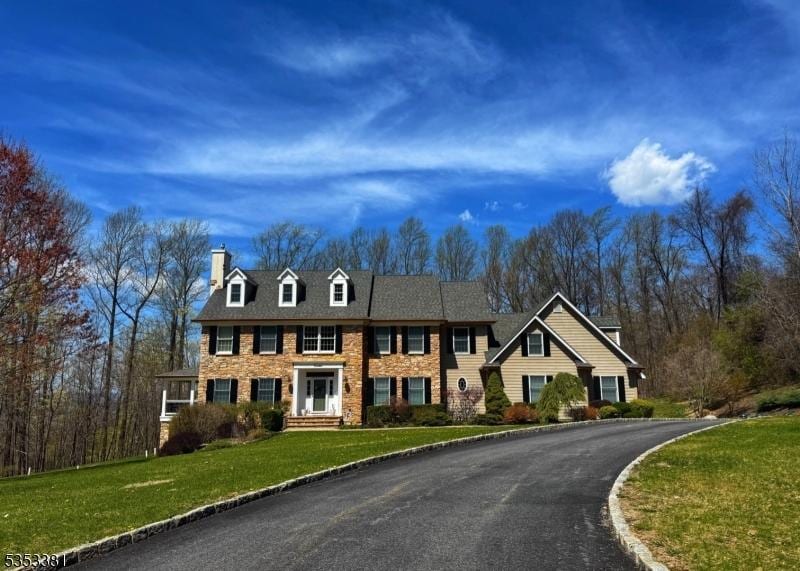view of front of house featuring driveway, a front yard, and a chimney