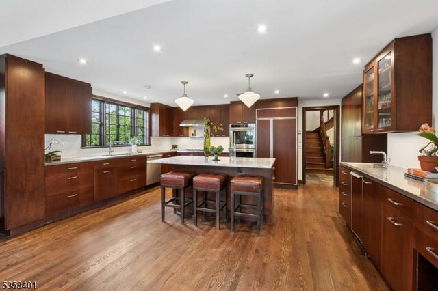 kitchen with a sink, a center island, a breakfast bar area, dark wood-style floors, and light countertops