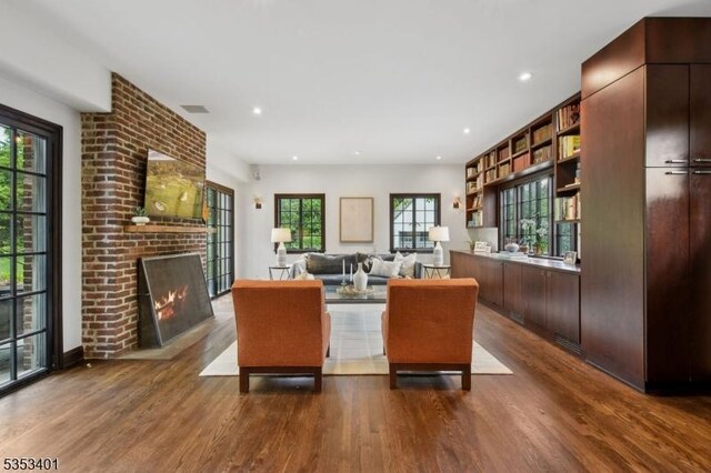 living room featuring dark wood-type flooring, healthy amount of natural light, a brick fireplace, and recessed lighting