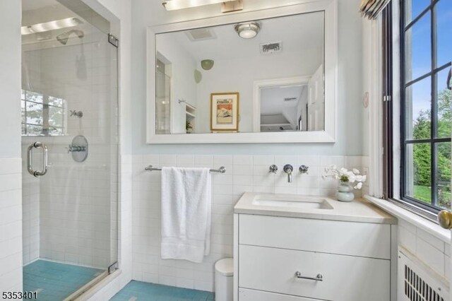 bathroom with radiator heating unit, a shower stall, vanity, tile walls, and toilet