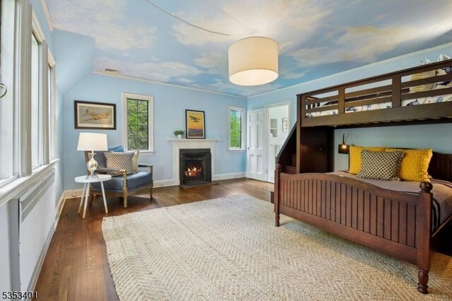 bedroom with wood finished floors, baseboards, and a fireplace with flush hearth