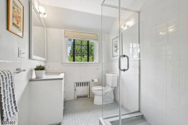 full bathroom with radiator heating unit, tile walls, a stall shower, toilet, and vanity