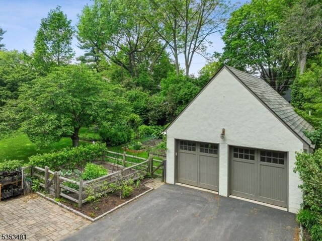detached garage with a vegetable garden and fence