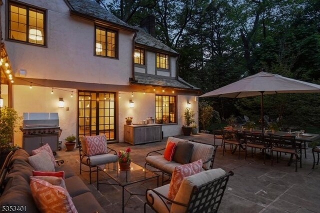 rear view of property with stucco siding, an outdoor living space, a patio area, a high end roof, and outdoor dining space