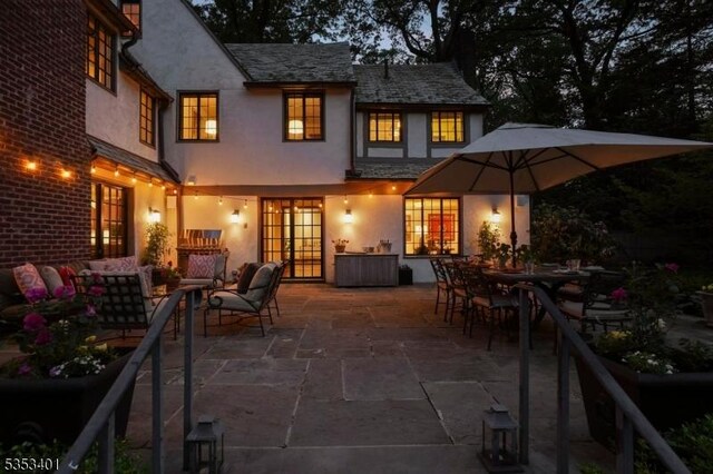 back of property featuring stucco siding, french doors, a patio, and a high end roof