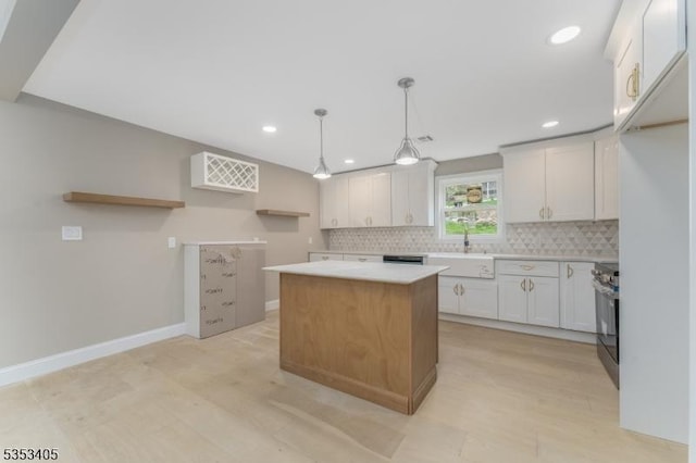 kitchen featuring recessed lighting, decorative backsplash, light countertops, a sink, and a center island