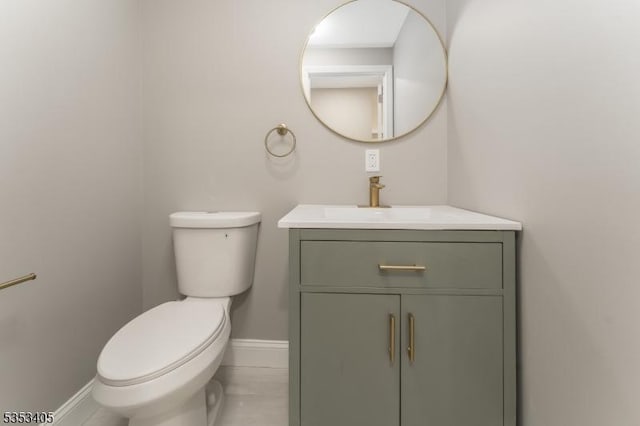 bathroom featuring toilet, vanity, and baseboards