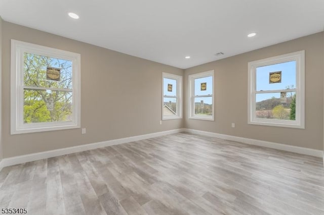 unfurnished room with recessed lighting, baseboards, light wood-style floors, and a healthy amount of sunlight