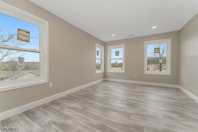 empty room featuring recessed lighting, light wood finished floors, and baseboards