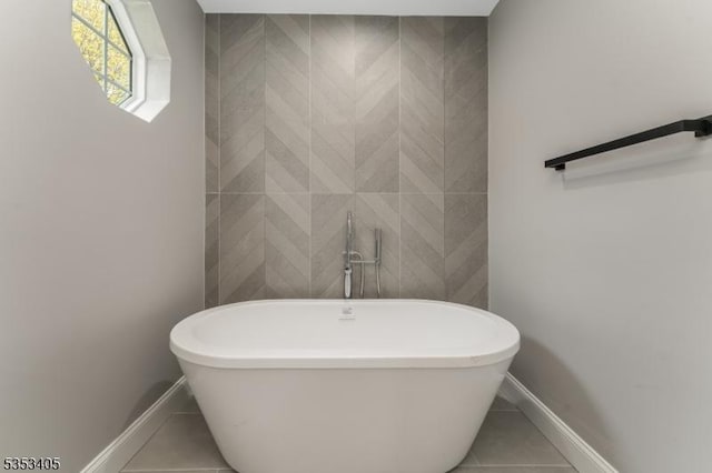 full bathroom featuring tile patterned flooring, a freestanding tub, and baseboards