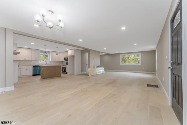 unfurnished living room with recessed lighting, light wood-style floors, a chandelier, and plenty of natural light