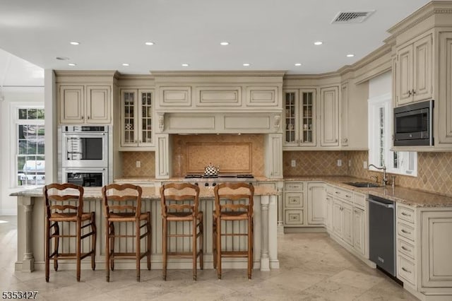 kitchen with visible vents, light stone counters, cream cabinetry, and stainless steel appliances