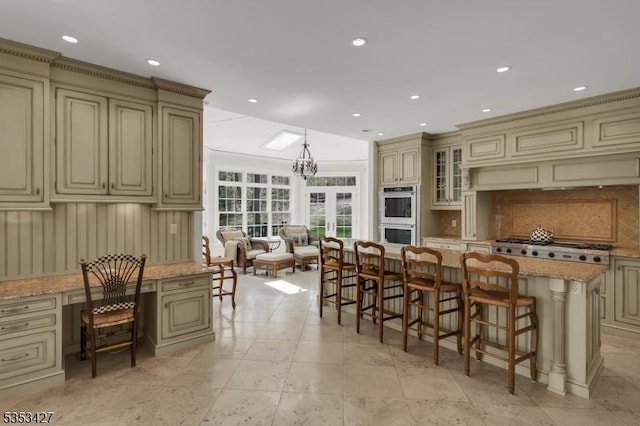 kitchen featuring a breakfast bar, a chandelier, cream cabinets, backsplash, and stainless steel appliances