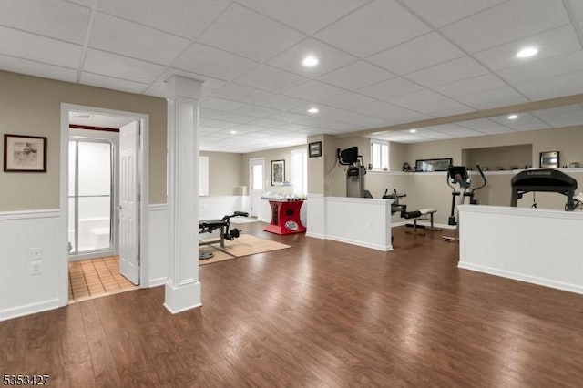 interior space with wainscoting, a drop ceiling, recessed lighting, and wood finished floors