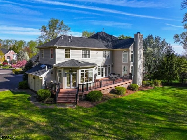 rear view of property featuring a lawn, a deck, french doors, and a chimney
