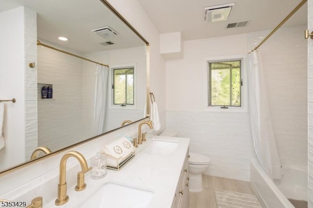bathroom with tile walls, visible vents, toilet, and a sink