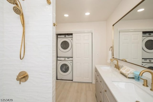 laundry area with stacked washer / drying machine, light wood-style flooring, and a sink