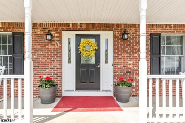 entrance to property with a porch and brick siding