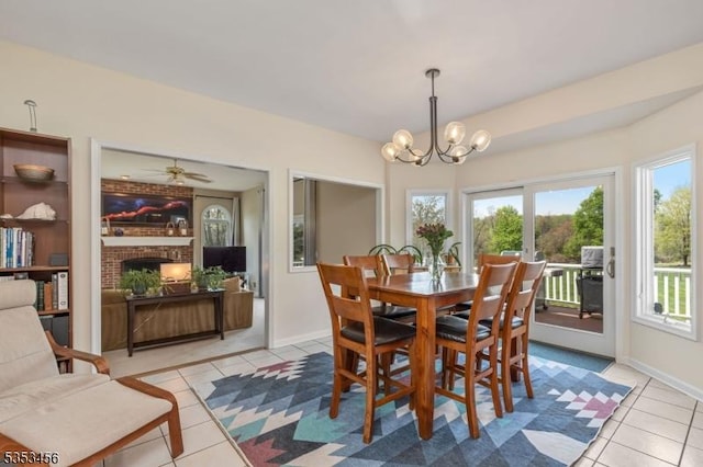 dining room featuring light tile patterned floors, baseboards, a fireplace, and a notable chandelier