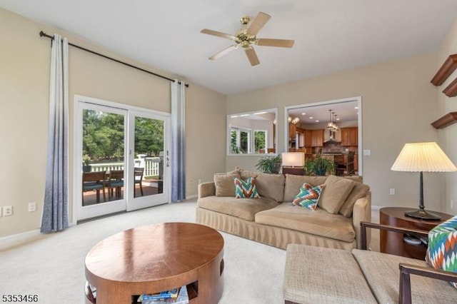 living area with a ceiling fan and light colored carpet