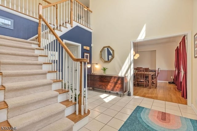 stairs with tile patterned floors and a high ceiling