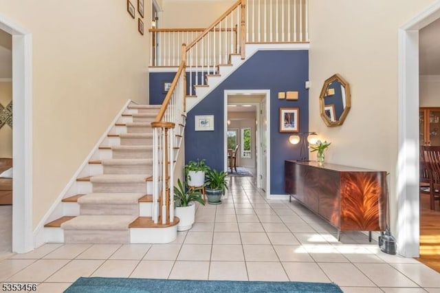 stairway featuring baseboards, tile patterned floors, and a high ceiling