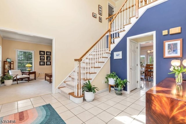 staircase featuring tile patterned flooring, carpet flooring, baseboards, and a towering ceiling
