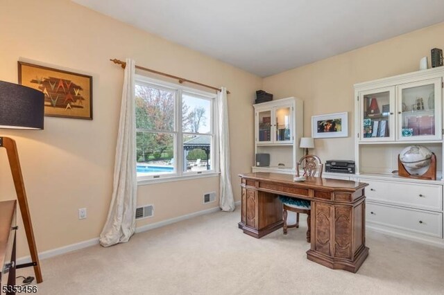 office area with baseboards, visible vents, and light carpet