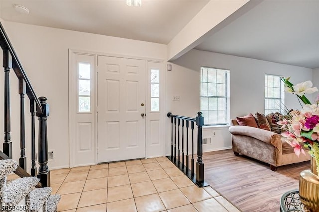 entryway featuring baseboards, stairs, light tile patterned flooring, and visible vents
