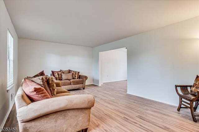 living area featuring baseboards, light wood-style flooring, and a wealth of natural light