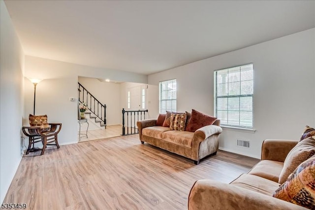 living area with visible vents, light wood-style flooring, and stairway