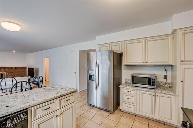 kitchen with light stone counters, cream cabinets, stainless steel appliances, and light tile patterned flooring