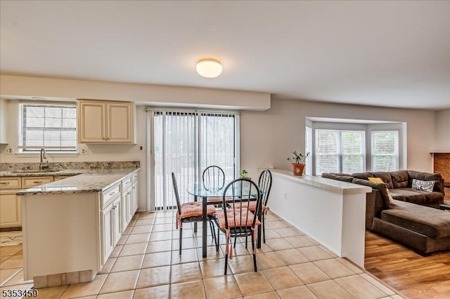 kitchen with a sink, cream cabinets, a peninsula, and open floor plan