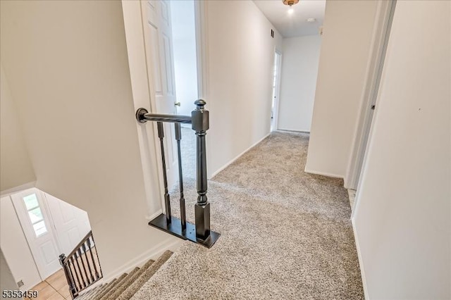 hall featuring baseboards and carpet flooring