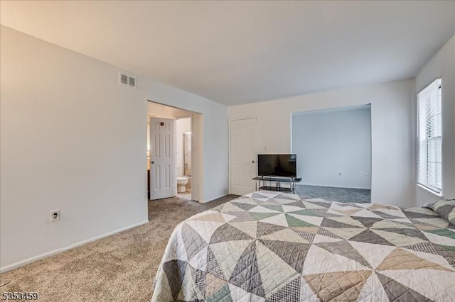 carpeted bedroom with connected bathroom, baseboards, and visible vents